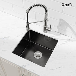Angled view of Cozy 18-inch matte black undermount single bowl handmade kitchen sink installed on white marble countertop