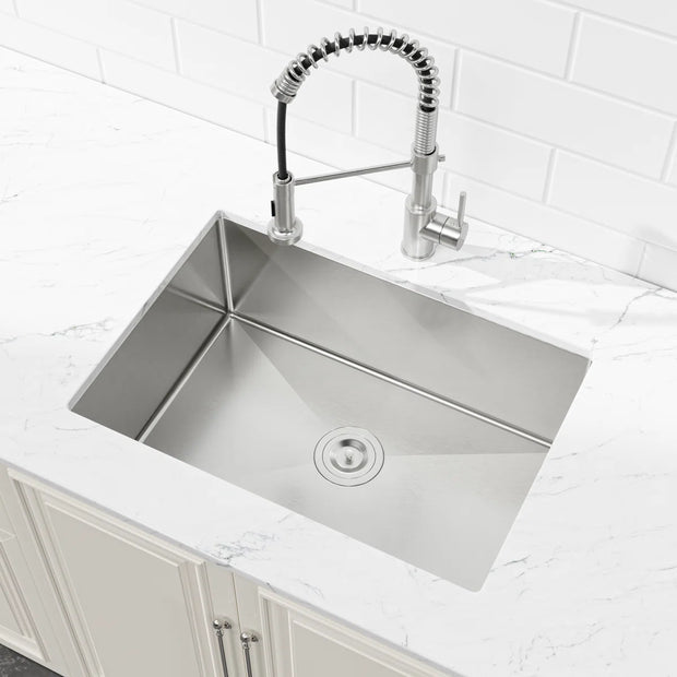Angled view of Cozy 27-inch brushed nickel undermount single bowl handmade stainless steel kitchen sink installed under white countertop